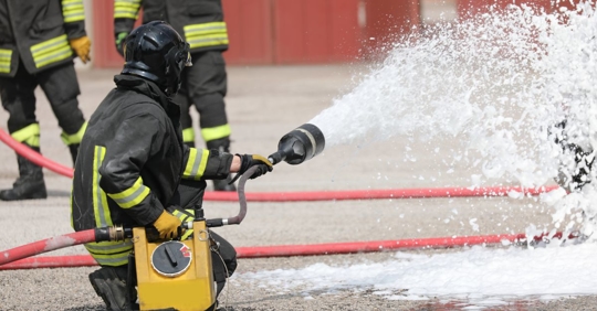Firefighter using foam to put out a fire